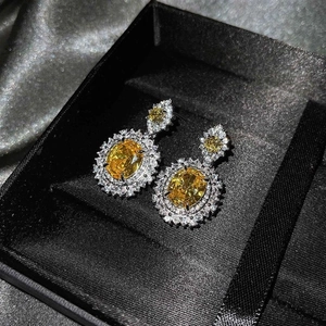 Primer plano de pendientes de lujo con gemas amarillas y halo de diamantes