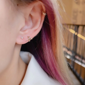 Three-piece set of gold snake-style ear cuffs and studs with rhinestones on female ear