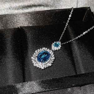 Vista detallada de un collar con gema azul ovalada y halo de diamantes en estuche negro