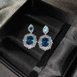 Detalle de pendientes vintage de plata con gema ovalada azul oscuro y diamantes blancos