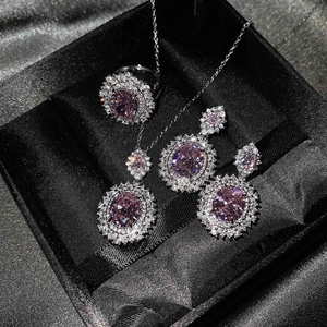 Vista detallada del conjunto de joyas con piedras rosas y engaste halo en estuche de lujo