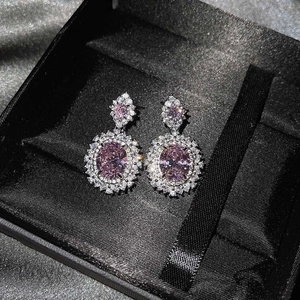 Primer plano detallado de pendientes largos de lujo en plata con gemas rosas ovales y halo