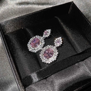 Detalle de pendientes con piedra rosa de corte ovalado y diseño halo en estuche de joya