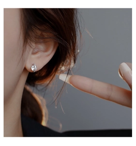 Macro shot of silver stud earring featuring a large round zircon with delicate curved accents