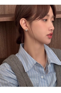 Gros plan détaillé de boucles d'oreilles boules en argent poli avec collier de perles