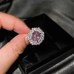 Primer plano de un anillo de lujo con gema rosa ovalada y doble halo de diamantes brillantes