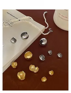 Détail de boucles d'oreilles boules dorées et argentées montrant la charnière et le poinçon