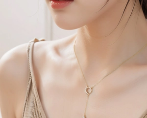 Close-up of a gold-plated tassel necklace with sparkling diamonds on a model's collarbone