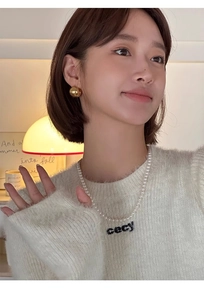Détail d'un collier de perles et de boucles d'oreilles boules dorées polies sur un mannequin