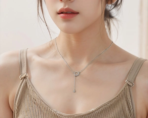 Detail of silver tassel necklace with crystal circle pendant worn on woman neckline
