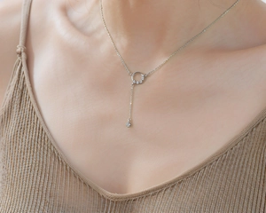Close-up of elegant silver tassel necklace with crystal pendant on a model's neck