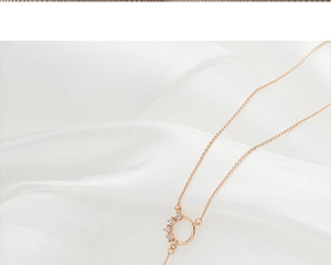 Close-up of elegant rose gold tassel necklace with crystal accents on white silk