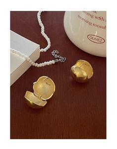 Détail des boucles d'oreilles boules dorées et collier de perles sur bois vintage