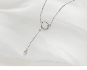 Macro shot of silver Y-shaped tassel necklace with crystal circle and drop pendant