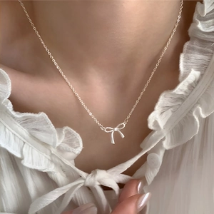 Elegant silver ribbon bow necklace on model wearing a white lace shirt for women