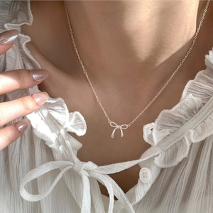 Elegant silver ribbon bow necklace on model with minimalist clavicle chain style