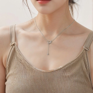Elegant silver tassel necklace with circular pendant and zircon drop on female model