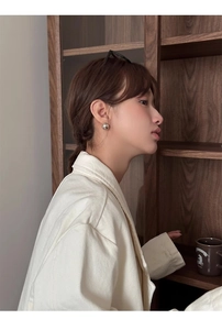 Gros plan d'une boucle d'oreille minimaliste en argent poli sur le mannequin