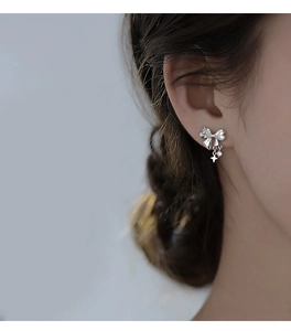 Silver bow stud earrings with sparkling star zircon pendants worn by a female model