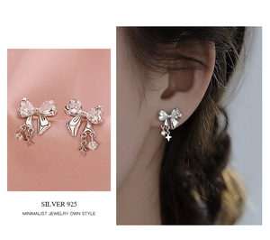 Detail of silver 925 bow stud earrings with white zircon and dangling crystal charms
