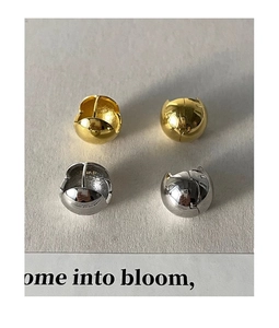 Gros plan de boucles d'oreilles boules polies or et argent sur surface texturée