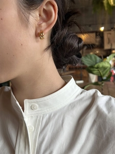 Gros plan d'une boucle d'oreille créole à maillons dorés portée par un mannequin pro