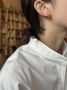 Boucles d'oreilles anneaux chaînées dorées portées par un mannequin au style épuré