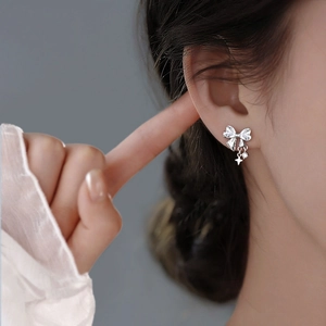 Elegant silver bow stud earrings with sparkling cubic zirconia and star charms on model