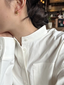 Vue détaillée d'une boucle d'oreille chaîne torsadée dorée sur une femme élégante