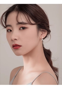 Close-up of model wearing silver fishtail pearl earrings with zircon detailing