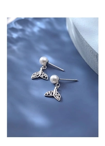 Detailed close-up of zircon fishtail and pearl earrings on a blue water ripple background