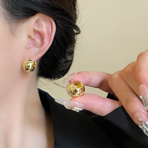 Boucles d'oreilles boules dorées élégantes avec finition polie portées par un mannequin