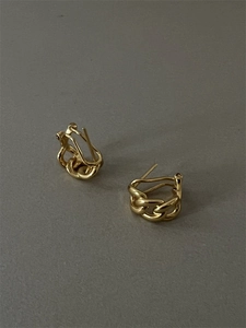 Détail de boucles d'oreilles créoles dorées avec texture de maille gourmette tissée