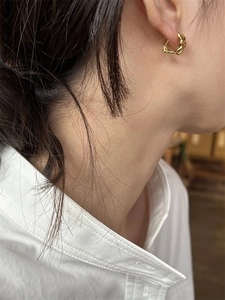 Gros plan d'une boucle d'oreille créole dorée torsadée au style moderne minimaliste