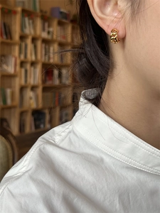 Gros plan d'un mannequin portant des boucles d'oreilles dorées avec maillons gourmette