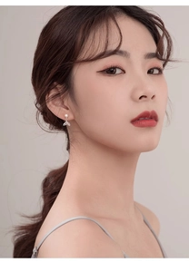 Close-up of elegant fishtail pearl stud earrings with zircon inlay worn by a model