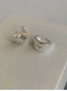 Close-up of silver geometric huggie earrings with polished finish and engraved details