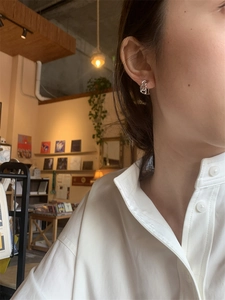 Gros plan de boucles d'oreilles en chaîne argentée portées par un mannequin en intérieur
