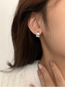 Close-up of a minimalist silver chunky hoop earring on ear with polished metallic finish