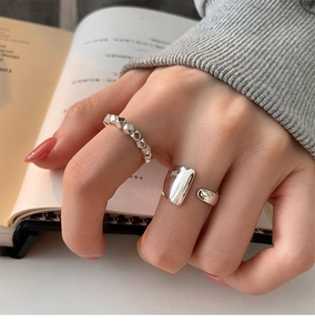 Primer plano de anillos de plata esterlina con texturas de tachuelas y banda lisa pulida