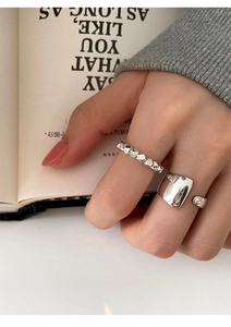 Detalle de anillos de cuentas de plata y banda ancha en el dedo con estilo minimalista