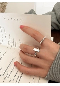 Detalle de anillo de cuentas plateado y banda grabada usados en un entorno cotidiano