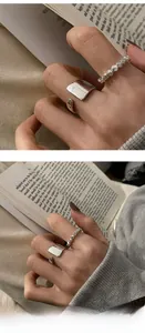 Detalle de anillo de plata con cuentas y anillo geométrico cuadrado en una mano