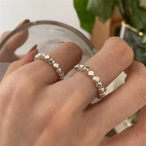 Primer plano de anillos de plata con cuentas metálicas facetadas irregulares en dedos