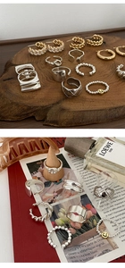 Plano cenital de anillos de plata con cuentas y joyas doradas sobre bloque de madera