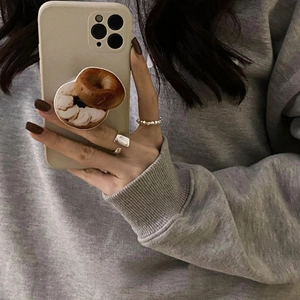 Soporte para móvil con diseño de bagel en funda beige con elegantes anillos de plata