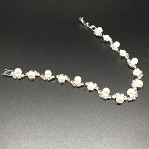 Dettaglio ravvicinato di un elegante bracciale di perle con strass scintillanti e maglie argento
