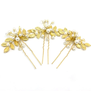 Vue détaillée de trois épingles à cheveux de mariée dorées avec perles et feuilles