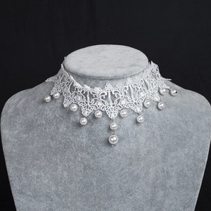 Detailed view of white lace choker necklace with hanging faux pearls for bridal styling