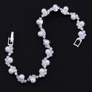 Vista macro di un elegante bracciale da sposa con perle bianche e strass brillanti sulla fascia